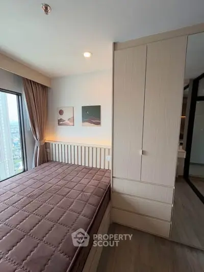 Modern bedroom with large window and stylish decor in high-rise apartment.