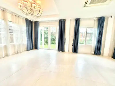 Spacious and bright living room with elegant chandelier and garden view.