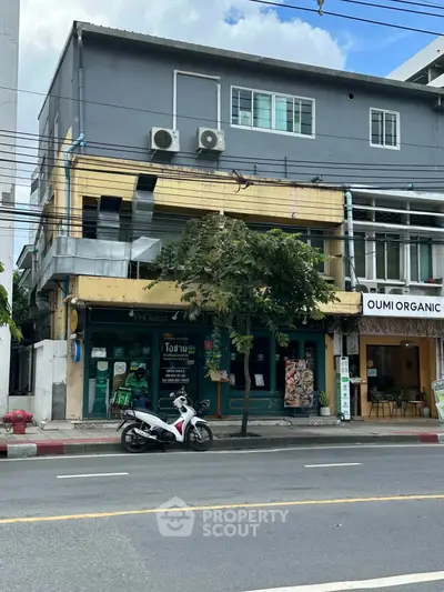 Street view of mixed-use building with retail shops and residential units above.