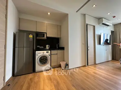 Modern apartment interior with kitchen and living area featuring wooden flooring and appliances.