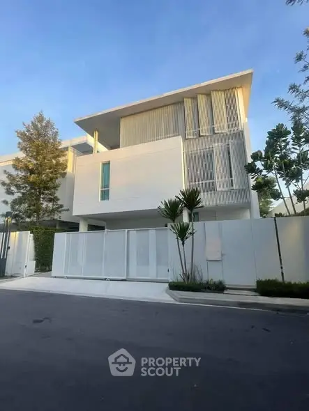 Modern minimalist white house with sleek design and lush greenery in a serene neighborhood.