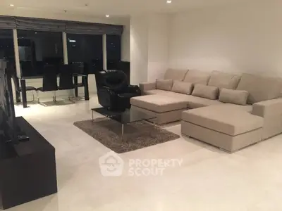 Spacious modern living room with large beige sectional sofa and sleek dining area.