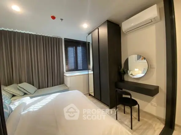 Modern bedroom with sleek design, featuring a cozy bed, stylish vanity, and air conditioning.