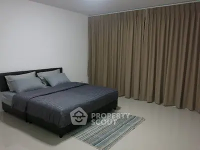 Spacious bedroom with modern decor and large window curtains