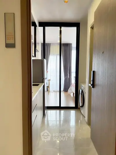 Modern apartment entrance with sleek kitchen and view into cozy bedroom