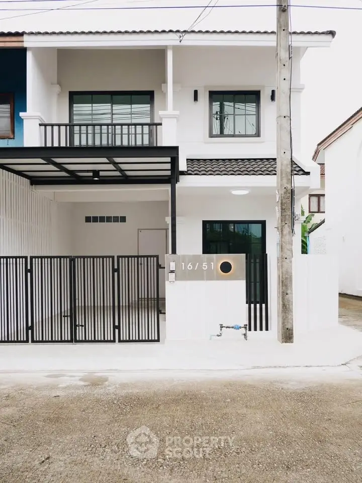 Modern two-story house with gated entrance and contemporary design.