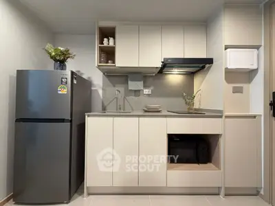 Modern kitchen with sleek cabinets and stainless steel fridge in a compact layout.