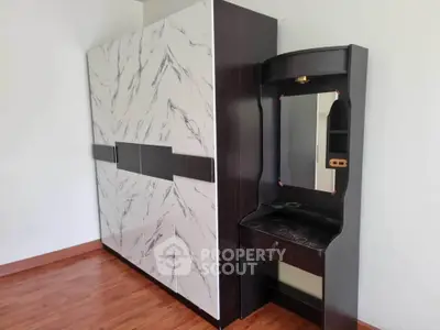 Spacious bedroom with elegant wardrobe and stylish vanity on wooden flooring.