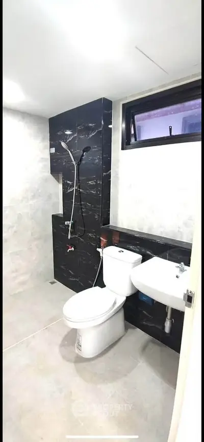 Modern bathroom with sleek black and white design, featuring a shower and toilet.