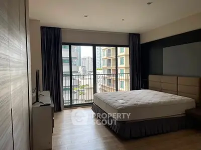Spacious bedroom with large window and city view, featuring modern decor and natural light.