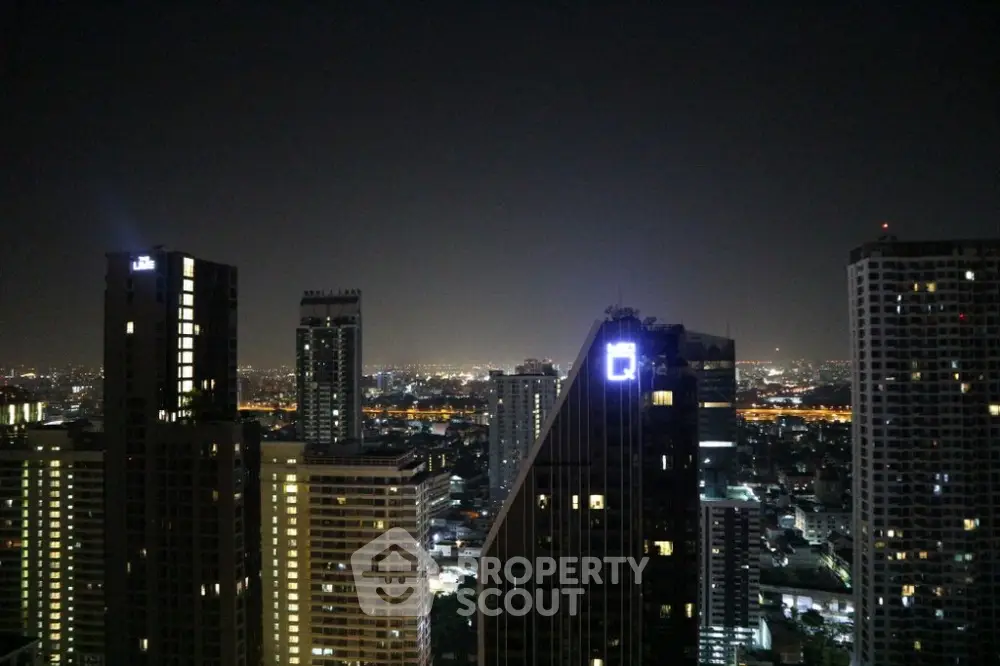Stunning city skyline view from high-rise apartment at night with illuminated buildings.
