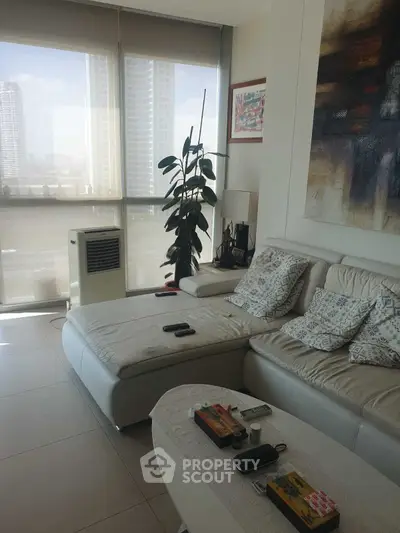 Modern living room with stylish decor and large windows offering city views.