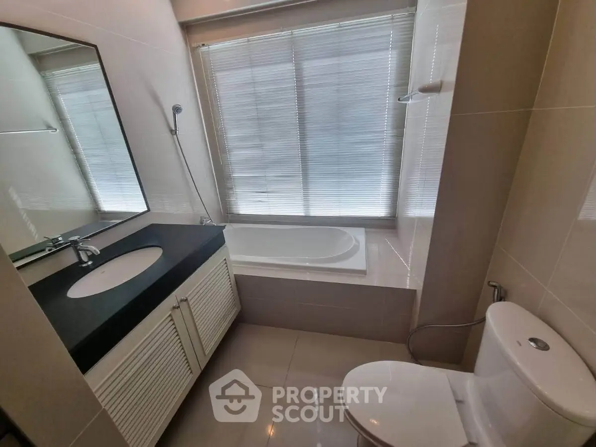 Modern bathroom with sleek fixtures and a bathtub under a large window.