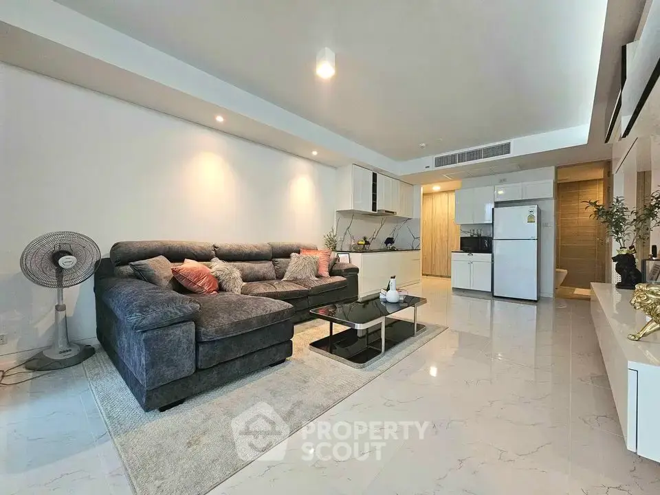 Spacious modern living room with plush sofa and sleek kitchen in open layout apartment.