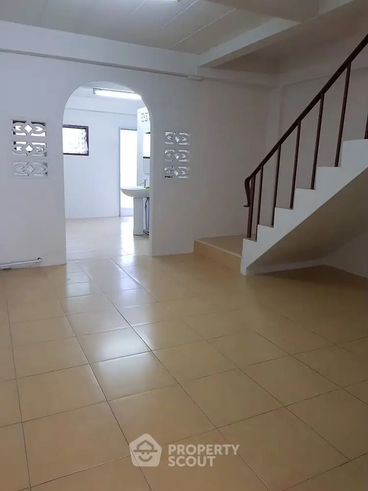 Spacious interior with tiled flooring and staircase, ideal for versatile living space.