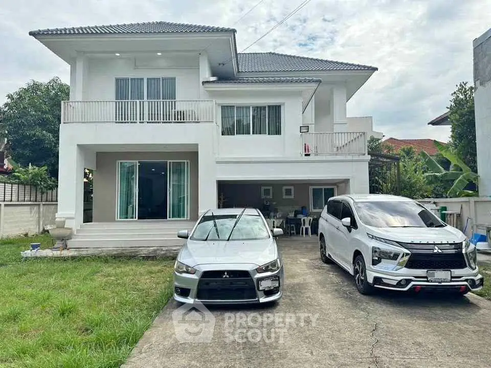 Spacious two-story house with driveway and two cars parked, ideal for family living.