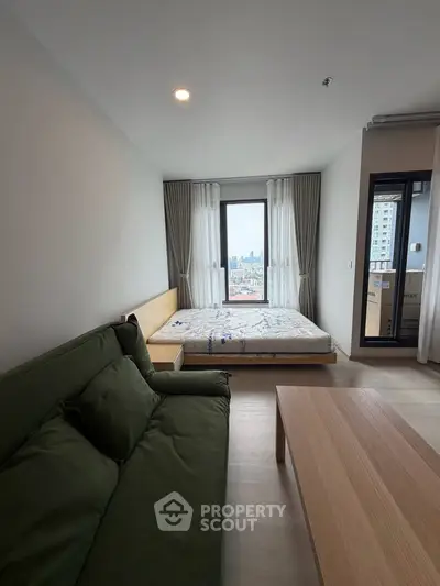 Modern bedroom with city view, featuring a cozy bed and stylish sofa, perfect for urban living.