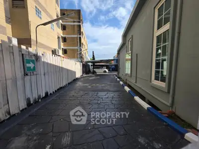 Spacious driveway leading to a modern building entrance with clear blue sky.