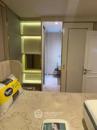 Modern bedroom with elegant decor and built-in shelving, featuring a cozy bed and stylish lighting.
