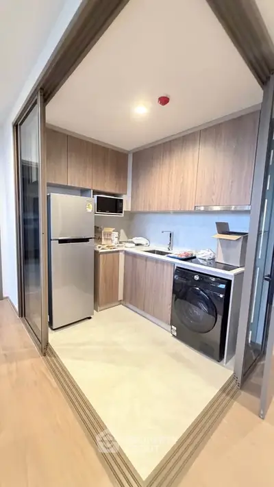 Modern kitchen with sleek appliances and wooden cabinetry in a stylish apartment.