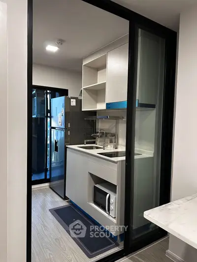 Modern compact kitchen with sleek appliances and sliding glass door