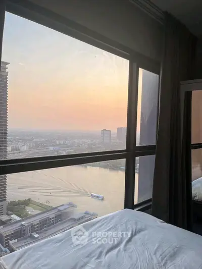 Stunning river view from a high-rise bedroom window at sunset, showcasing urban skyline and serene waters.