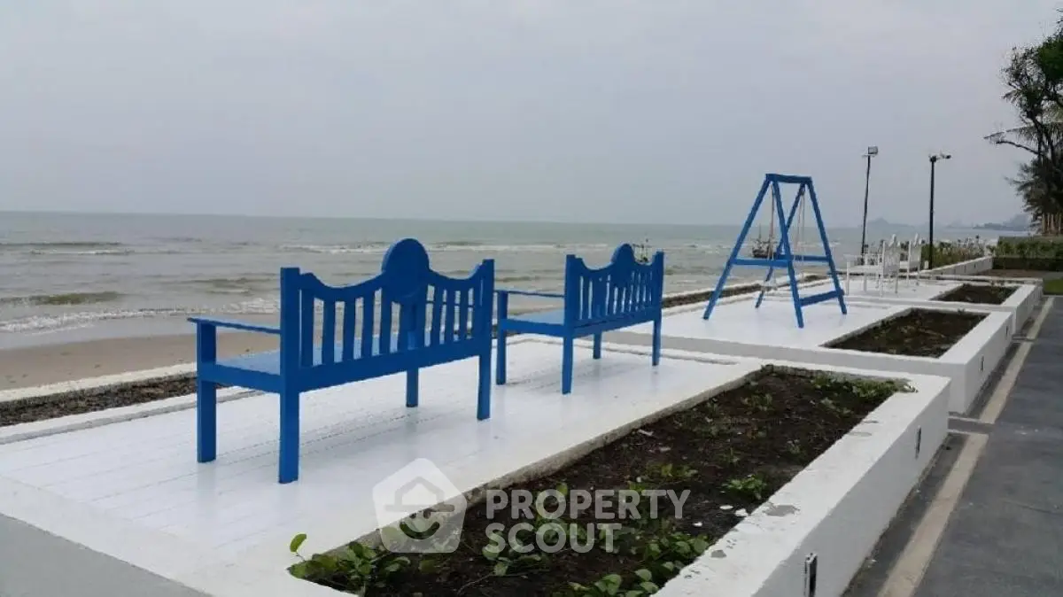 Stunning beachfront view with blue benches and swing, perfect for relaxation and leisure.