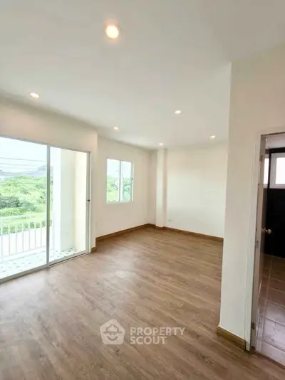Spacious and bright living room with wooden flooring and large windows offering scenic views.