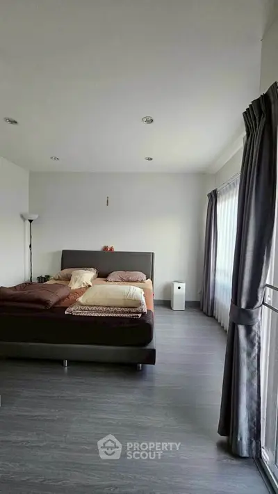 Spacious bedroom with modern decor and large windows for natural light.