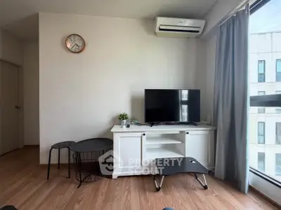 Modern living room with sleek TV setup and air conditioning, featuring large window for natural light.