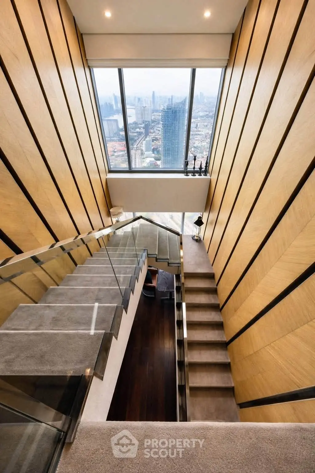 Stunning modern staircase with panoramic city view, featuring sleek glass railings and elegant wood paneling.