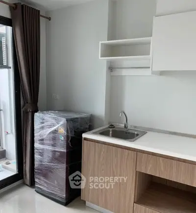 Modern kitchen with sleek cabinetry and compact fridge in a bright apartment