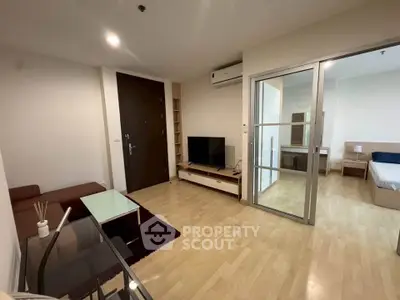 Modern living room with wooden flooring and glass partition leading to bedroom