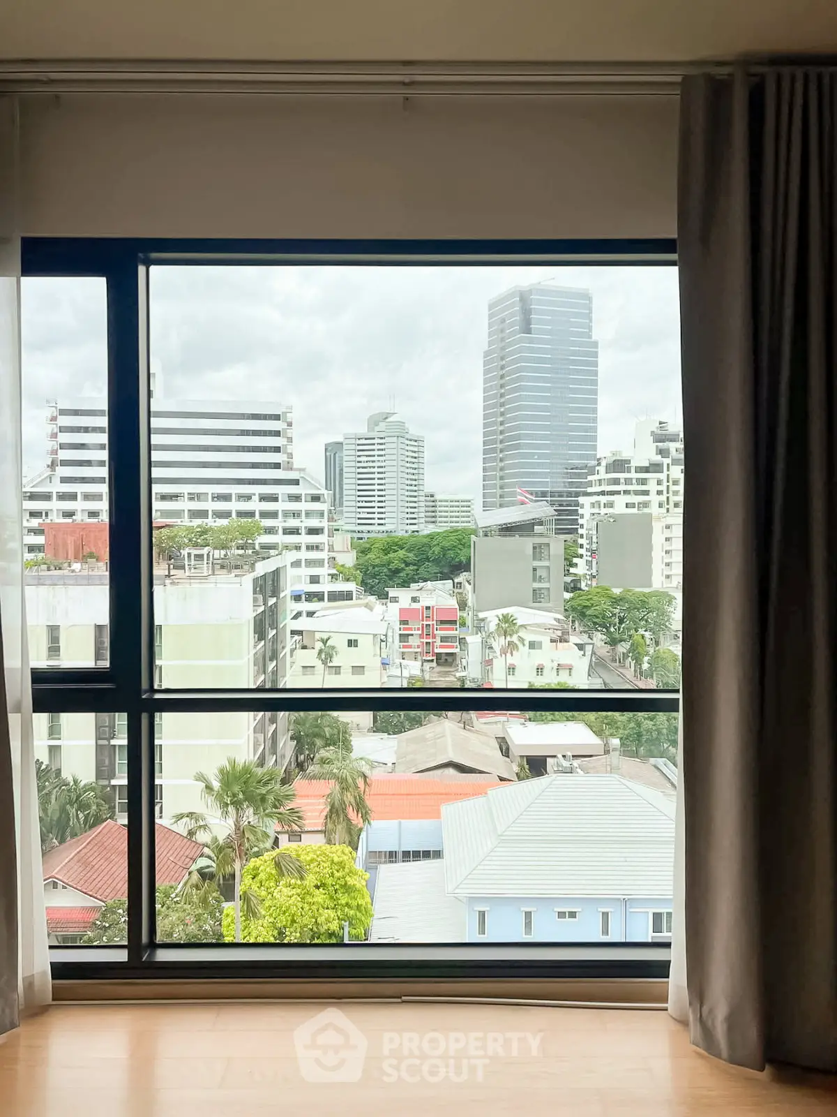 Stunning cityscape view from a modern apartment window, showcasing urban living with lush greenery and skyline.