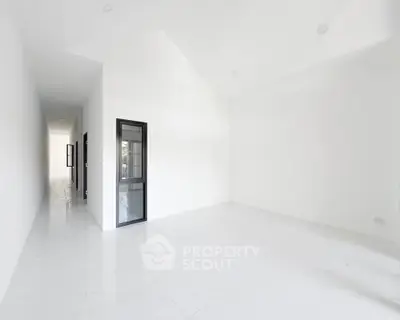 Spacious minimalist interior with high ceilings and sleek white flooring, perfect for modern living.