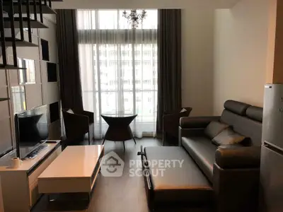 Modern living room with high ceiling, large windows, and stylish furniture in a contemporary apartment.
