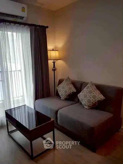 Cozy living room with modern sofa and elegant floor lamp near large window.