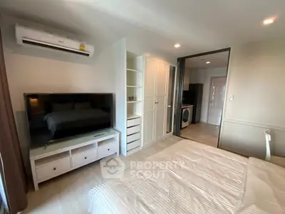 Modern bedroom with TV, air conditioning, and washing machine in a sleek apartment.