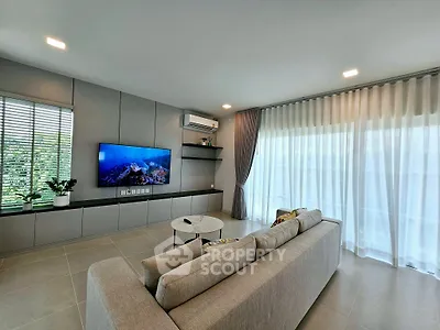 Modern living room with sleek design, large TV, and natural light from floor-to-ceiling windows.