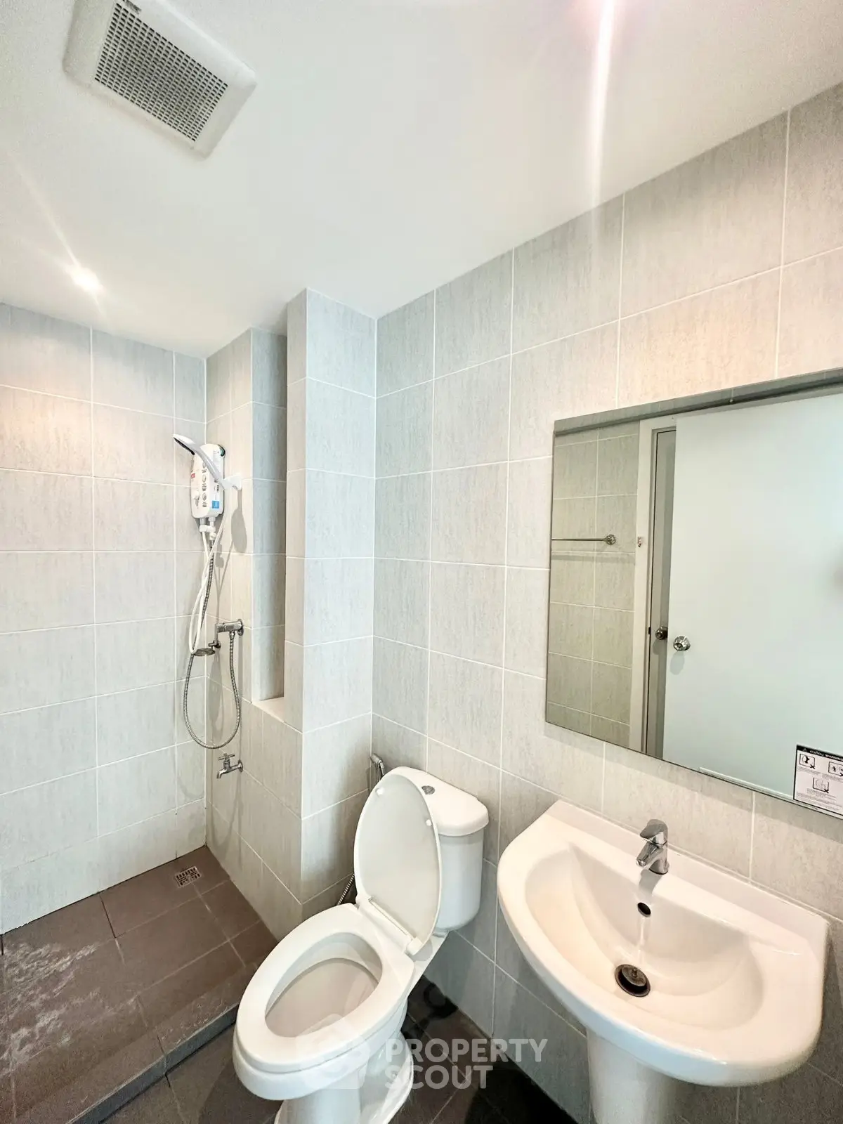Modern bathroom with shower, toilet, and sink in a tiled setting.