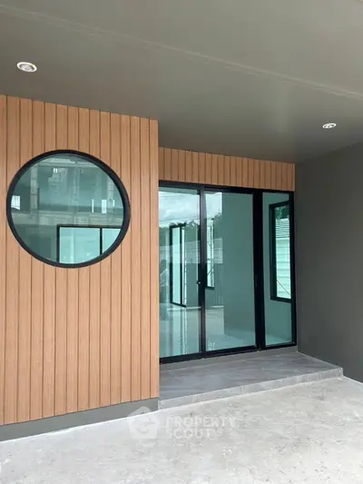 Modern entrance with circular window and sliding glass doors in contemporary home