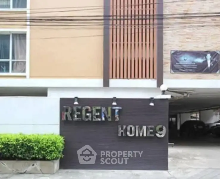 Distorted image of a building exterior with visible car and plants.
