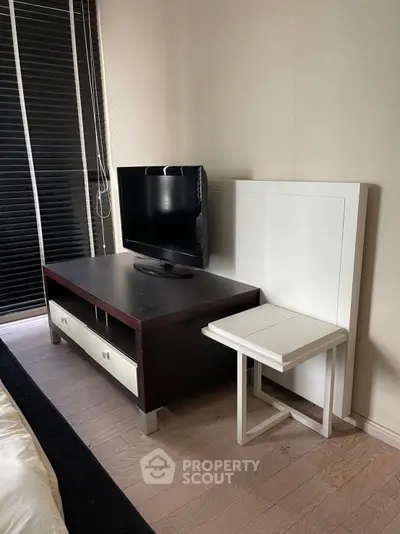 Modern bedroom with sleek TV stand and minimalist decor, featuring a cozy ambiance and stylish wooden flooring.