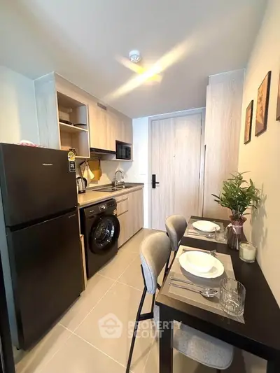Modern kitchen with dining area, featuring sleek appliances and stylish decor in a compact layout.