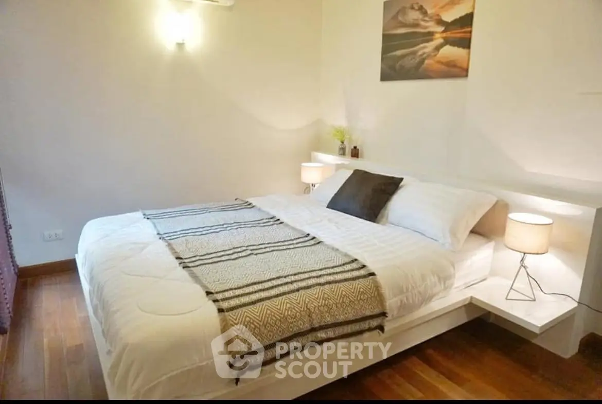 Cozy bedroom with modern decor and soft lighting, featuring a comfortable bed and elegant wooden flooring.