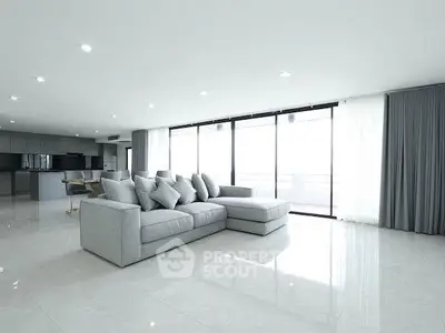 Spacious modern living room with large windows and sleek gray sofa in luxury apartment.