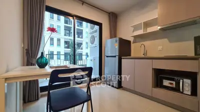 Modern kitchen with sleek cabinetry, dining area, and balcony view in a stylish apartment.