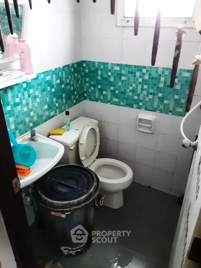 Compact bathroom with mosaic tiles and essential fixtures