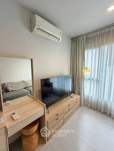 Modern living room with sleek TV unit and air conditioning, featuring natural light from large windows.