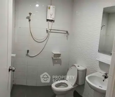 Modern bathroom with shower, toilet, and sink in a sleek white tile design.
